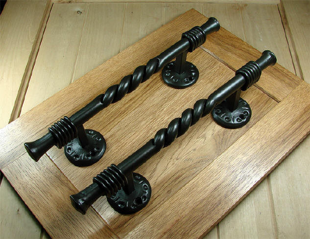 A pair of dark bronze Florence Tuscan pulls, used for opening doors or drawers, displayed on a cabinet door.