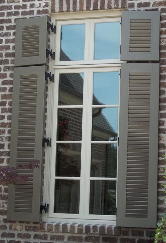 Black hinges installed between a window and green shutters