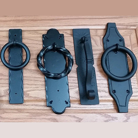 Four matte black door knockers displayed on a wooden background