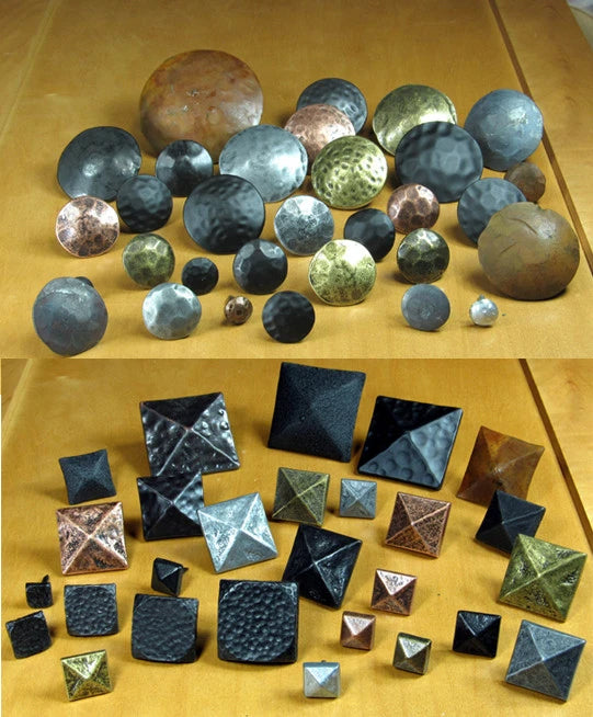 An assortment of square and circular clavos door pins in silver, brass, black, and hammered finishes.