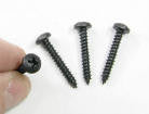 A photo of four pan head screws. One of the screws is being held between a person's index finger and thumb.