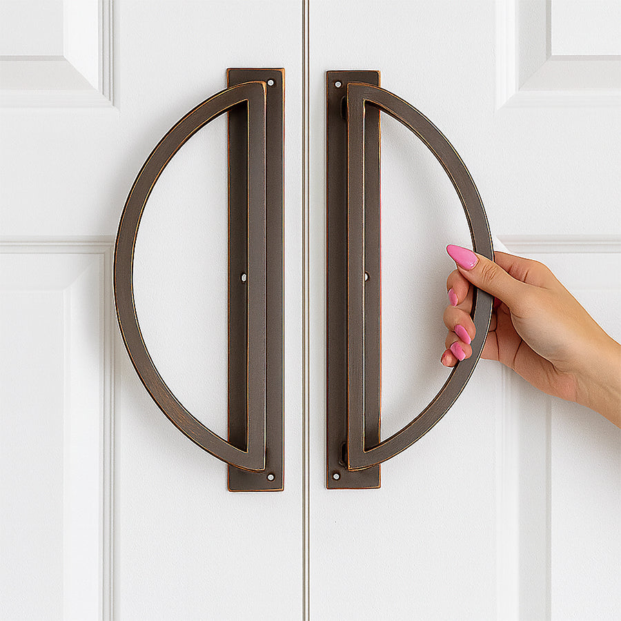 Hand opening a door with large bronze handles on a white background