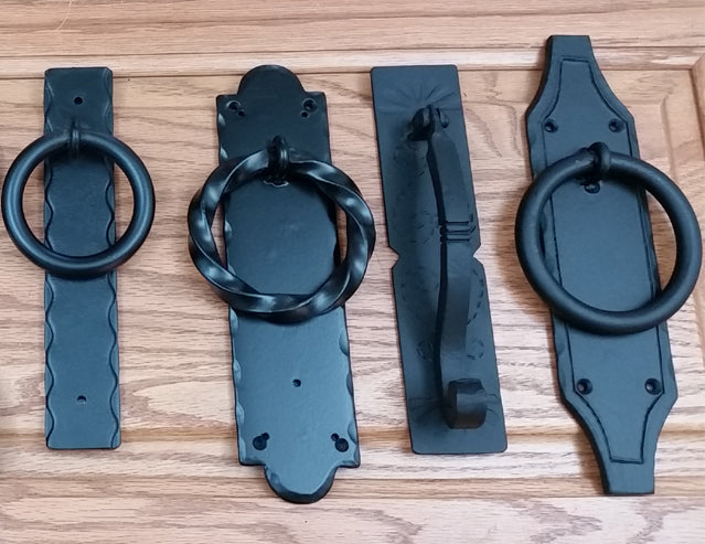 Four matte black door knockers displayed on a wooden background