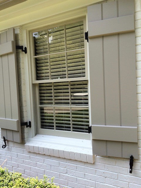 Black hinges installed between a window and green plank-styled shutters